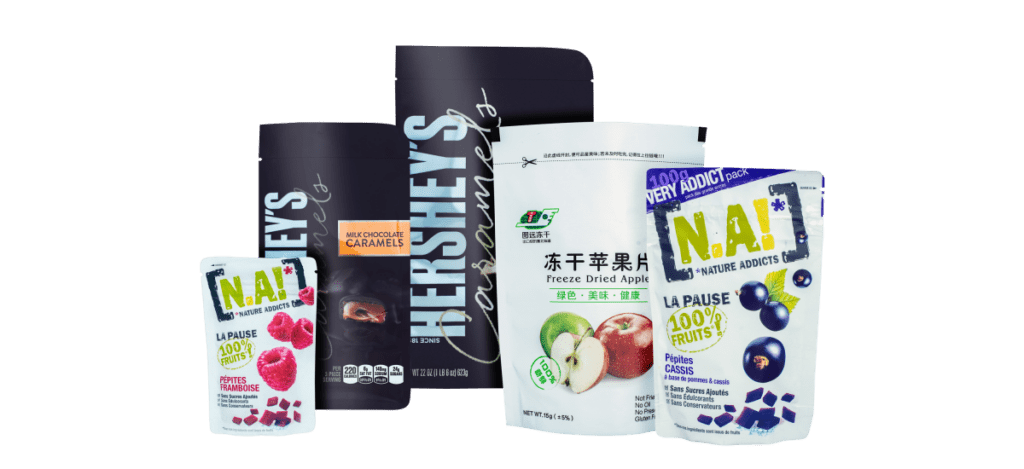 A selection of packaged foods, expertly prepared using state-of-the-art packing machinery: Hershey's caramel, freeze-dried apple slices, and N.A! raspberry and blueberry fruit snack bags.