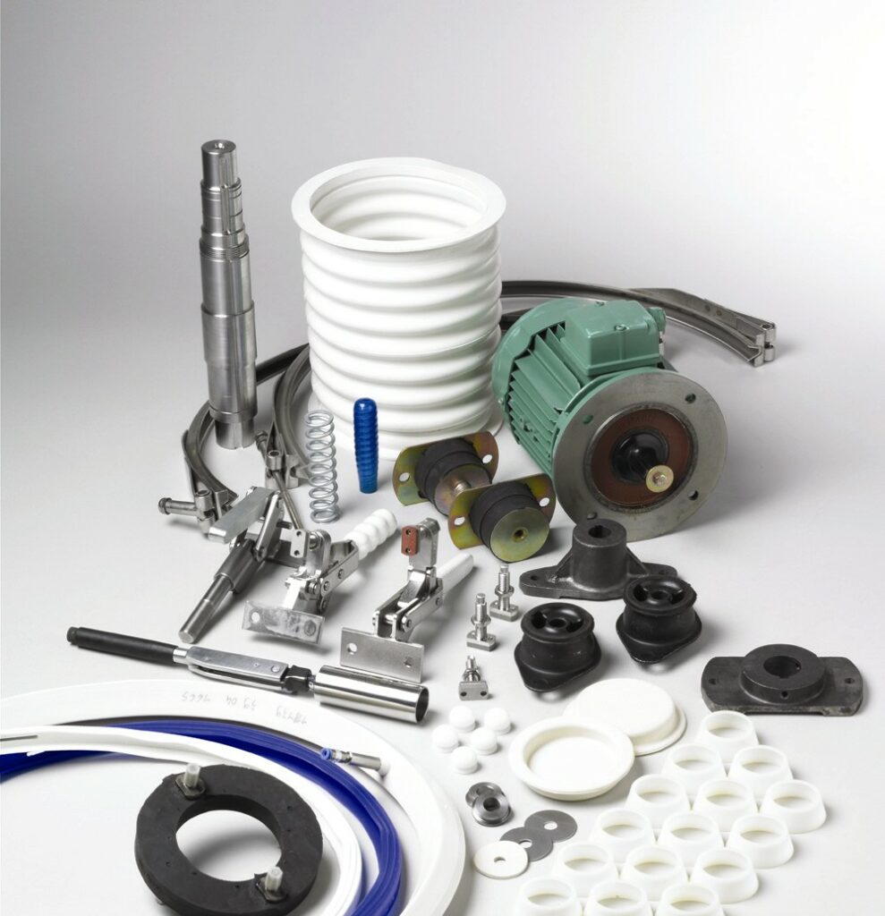 Various mechanical components, including an electric motor, coils, pipes, seals, and fittings crucial for process improvement, are meticulously arranged on a white surface.