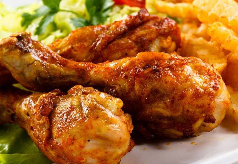 Grilled chicken drumsticks with perfectly seasoned skin, served alongside crinkle-cut fries and a fresh garnish of greens on a plate, embodying the art of food processing at its finest.